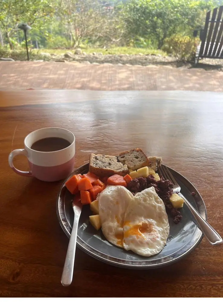 Breakfast of eggs, fruit and coffee on a wooden table