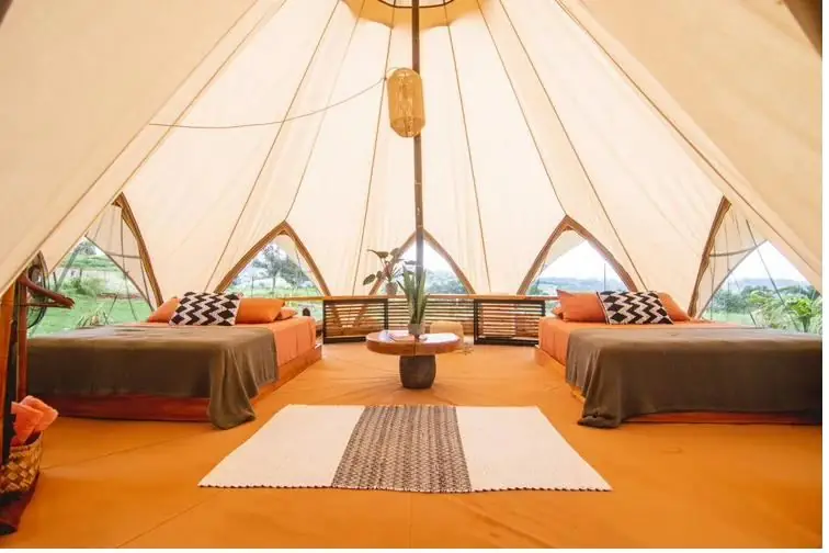 Inside a star tent: two queen beds facing a view of the valley