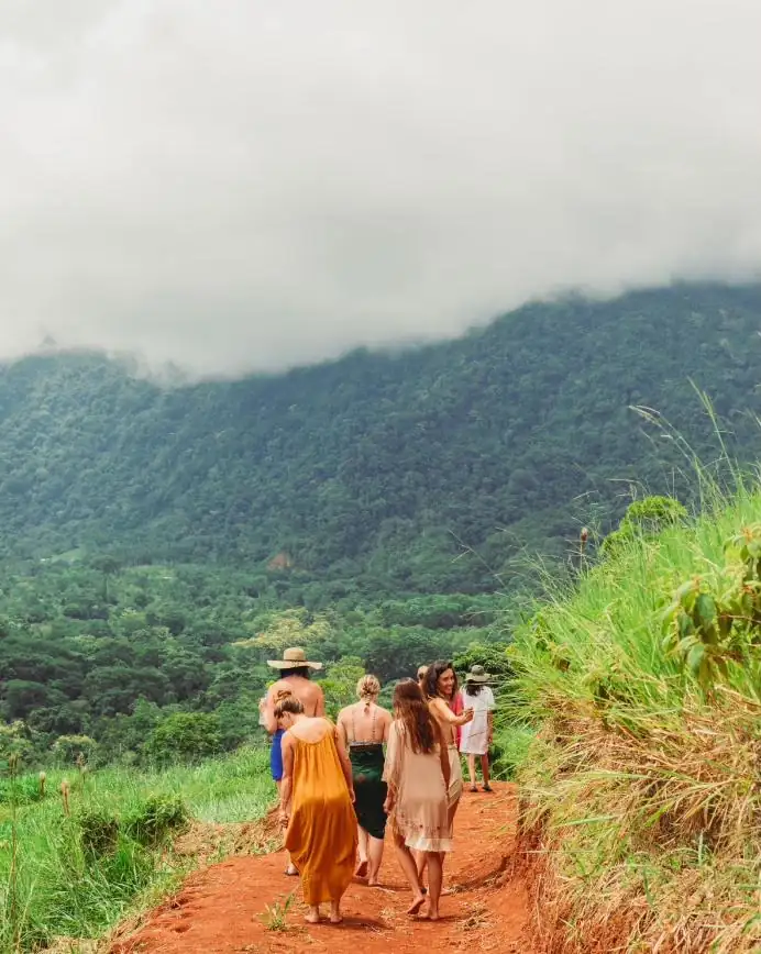 Guests walking the red-dirt ridge trail into the clouds